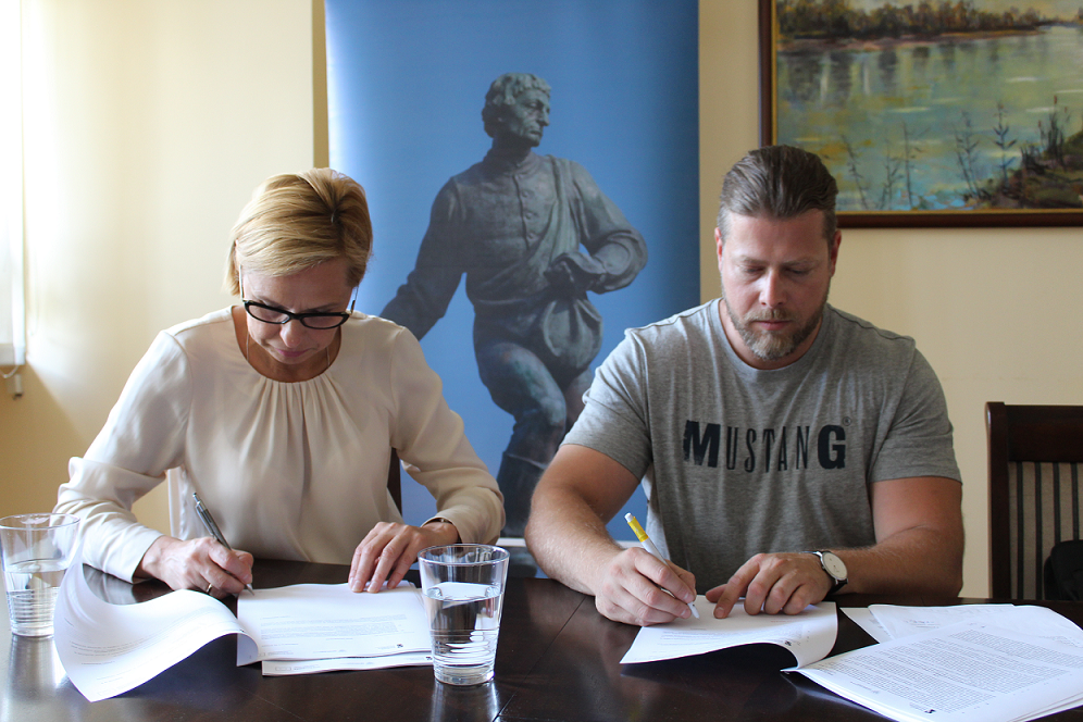 Na zdjęciu widać dwie osoby podpisujące umowy.
