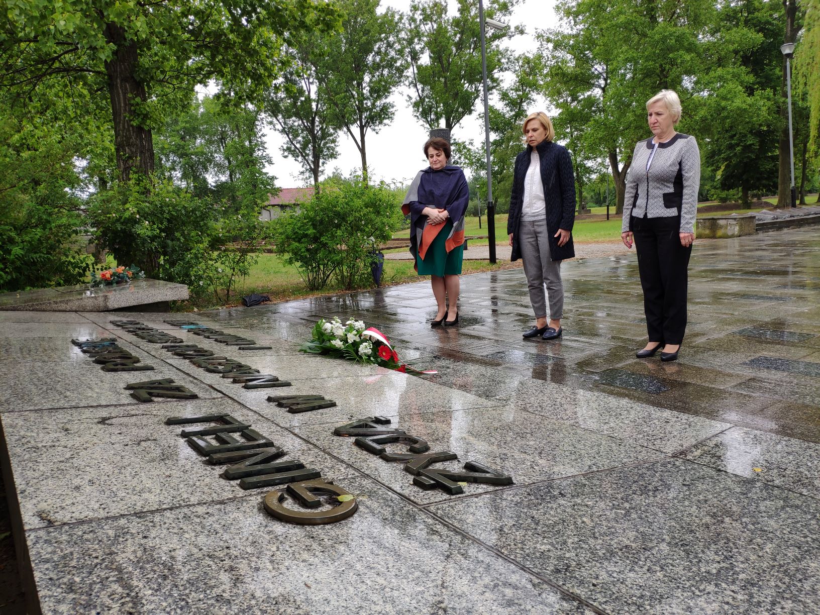 zdjęcie przedstawia Panią Burmistrz Małgorzatę Machalską, zastępcę Burmistrza Panią Dorotę Franek oraz Przewodniczącą Rady Miasta Luboń Panią Teresę Zygmanowską składające kwiaty pod pomnikiem